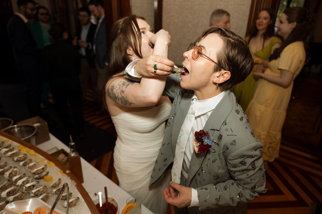 Bride and sister sharing oysters together during the reception, playful candid captured on film.