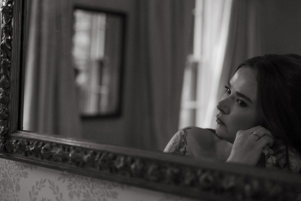 Bride reflected in a vintage mirror, lost in thought before the ceremony.