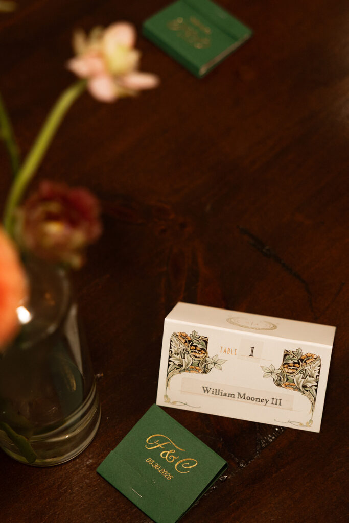 Green and gold escort card details on wooden table, intimate reception styling.