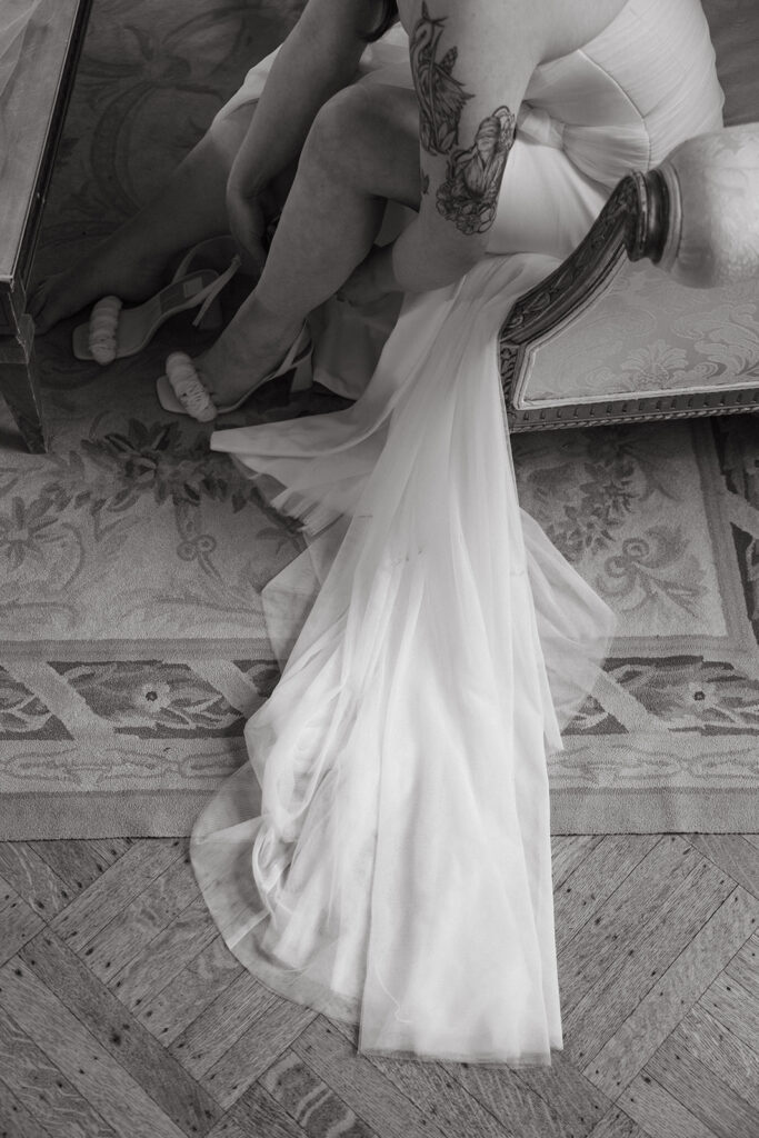 Bride’s dress trailing on vintage rug, detail of train and textures.