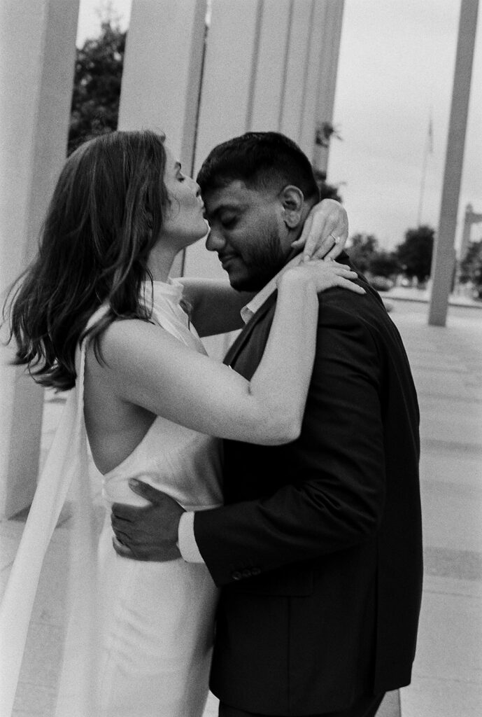 Couple embracing on city steps, black-and-white engagement photo with cinematic energy.