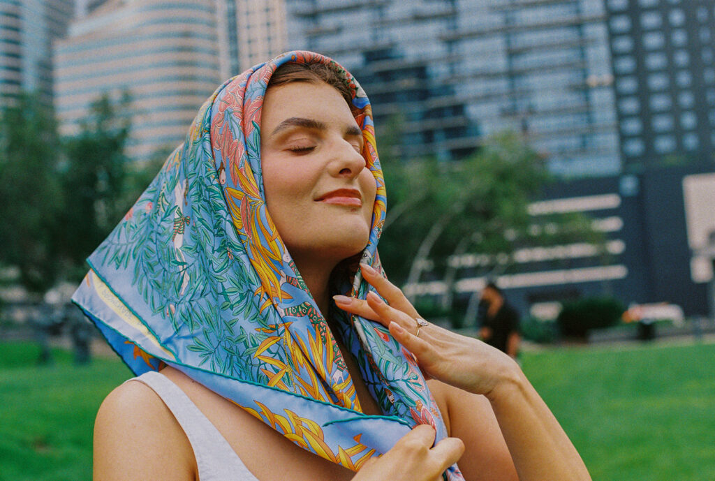 Bride in patterned silk scarf, eyes closed and face lifted toward the light, vintage-inspired engagement styling.