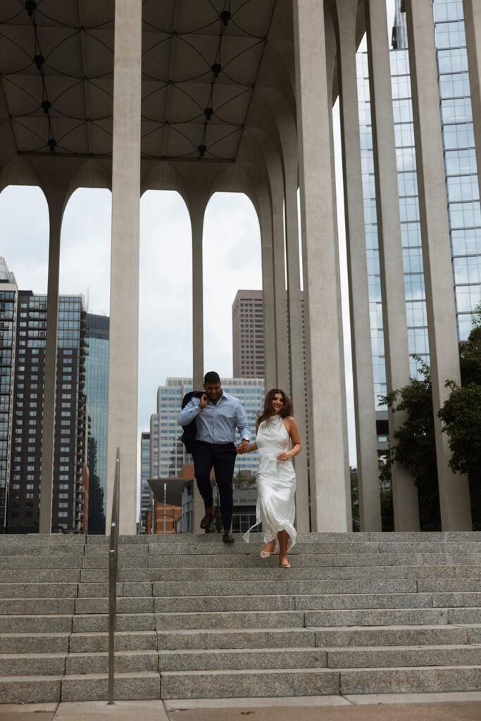 Couple walking hand-in-hand down the steps of the Northwestern National Life Building during their Minneapolis engagement session.