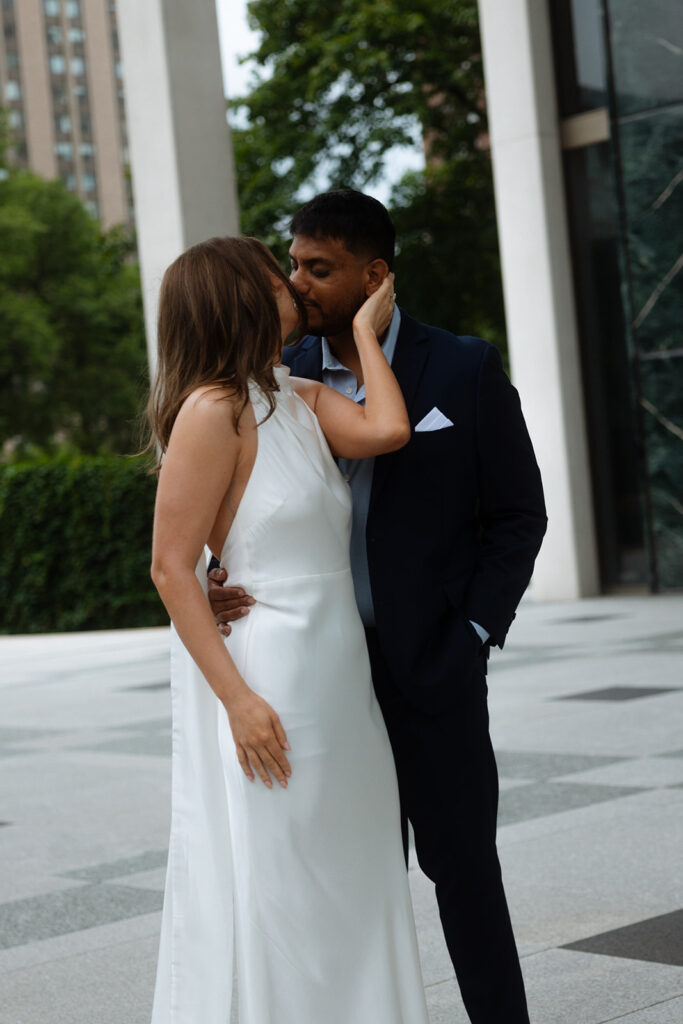Bride smiling while groom leans in close, captured in natural light during a Minneapolis engagement session.