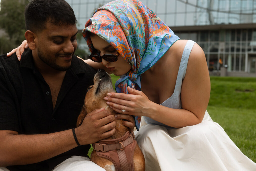 Groom smiling while bride pets their dog, joyful Minneapolis engagement session detail.