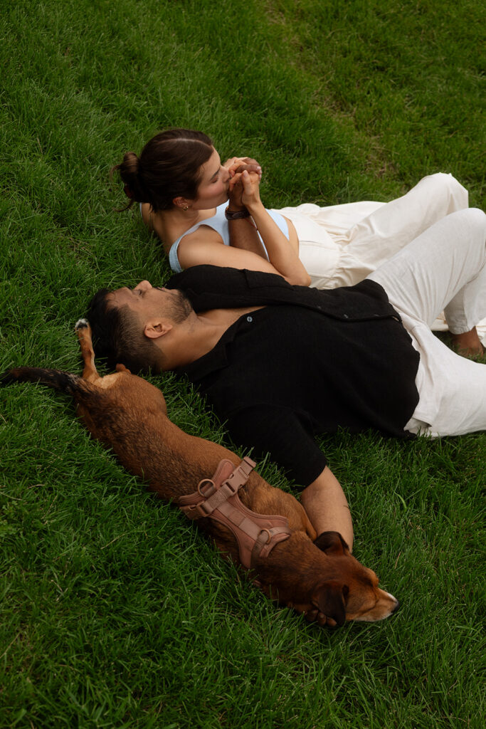 Couple and their dog lying in the grass together, captured by a Minneapolis engagement photographer.