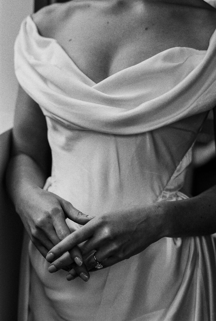 She holds her hands together over her gown, taking a quiet moment to breathe in posed wedding photography.