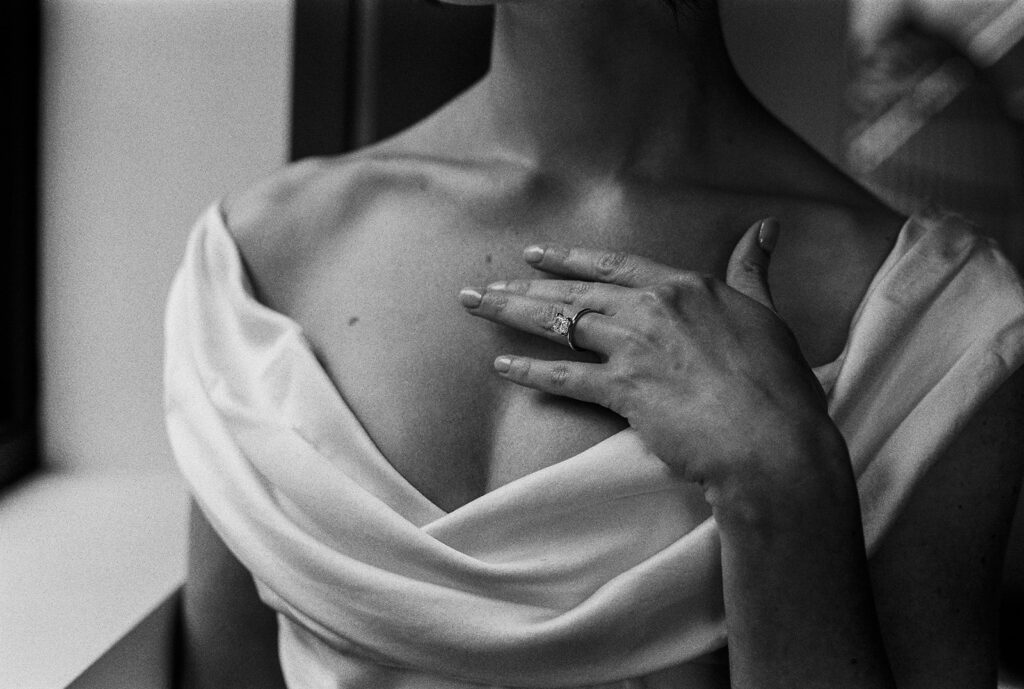 Hand resting against her collarbone, ring gleaming in window light — one of my favorite bridal portraits in posed wedding photography.