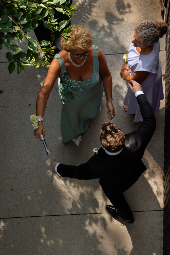 Friends greet one another on the path, hugging and finding their seats.