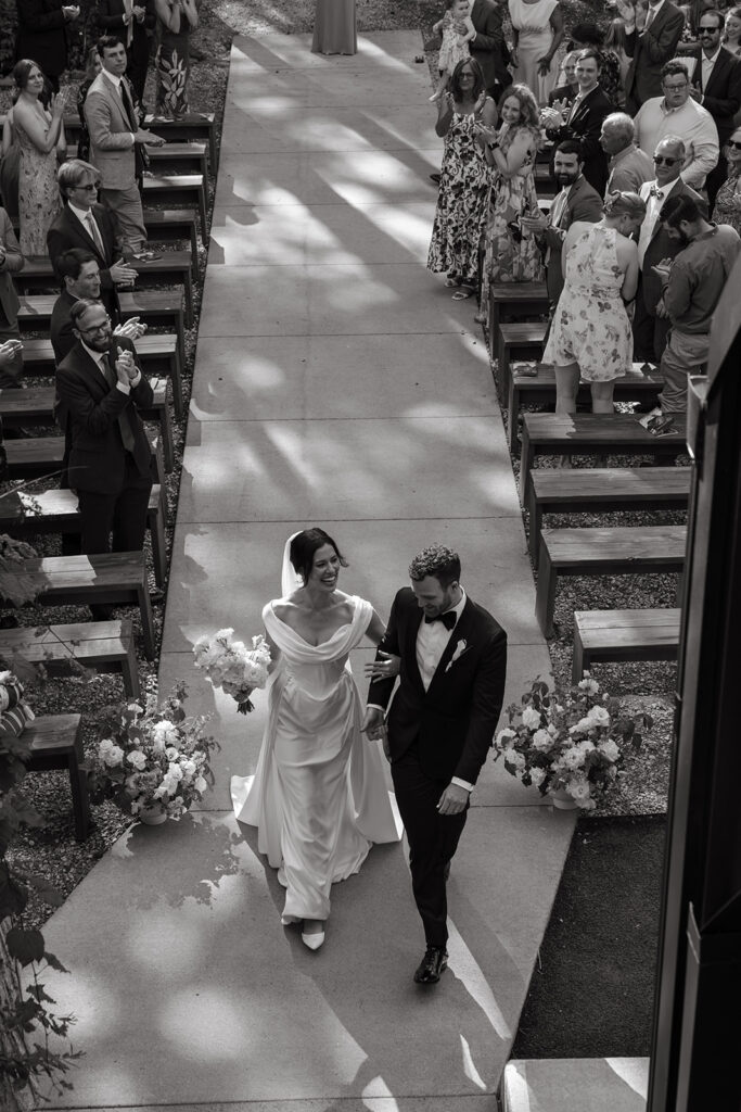 Bride and groom walking back up the aisle at Pinewood together, still grinning, still in disbelief.