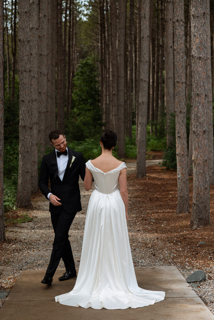 First-look moment under the tall pines at Pinewood in Cambridge, Minnesota