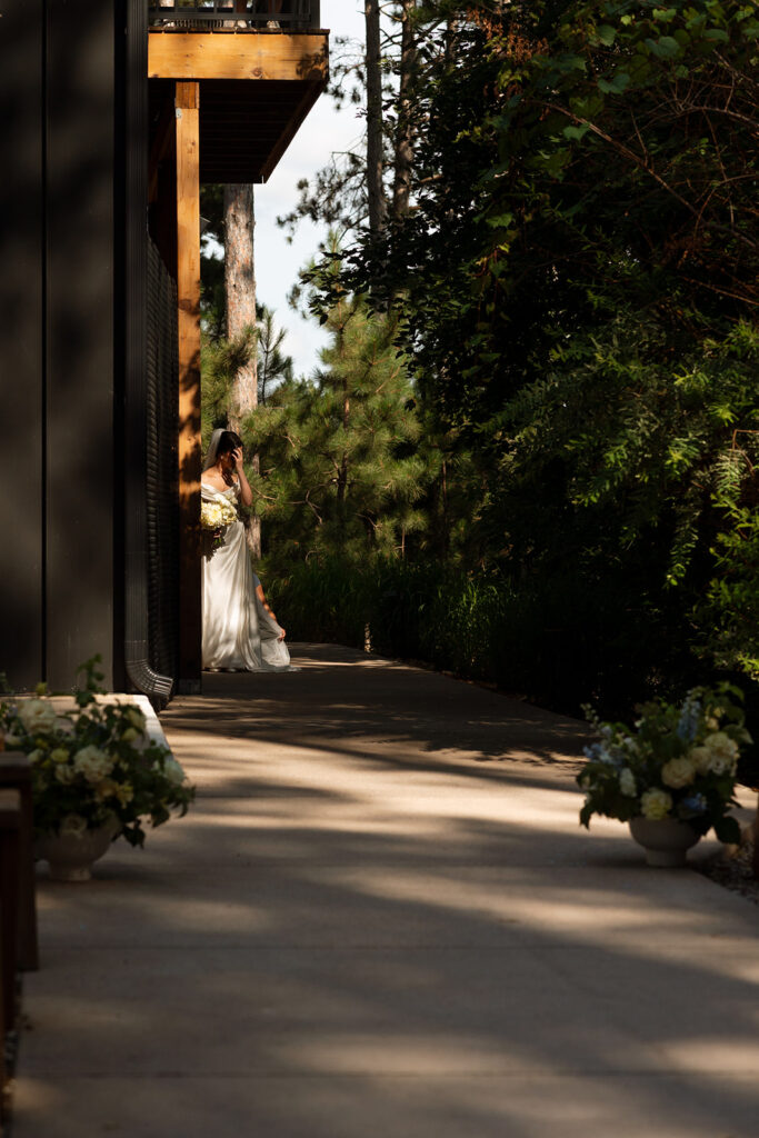 Bride framed in shadow and light outside Pinewood’s modern walls.