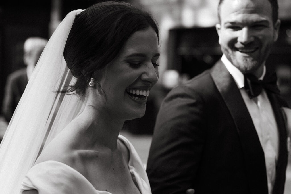 Emma and Isaac caught mid-laugh — the kind of posed wedding photography that doesn’t feel posed at all.