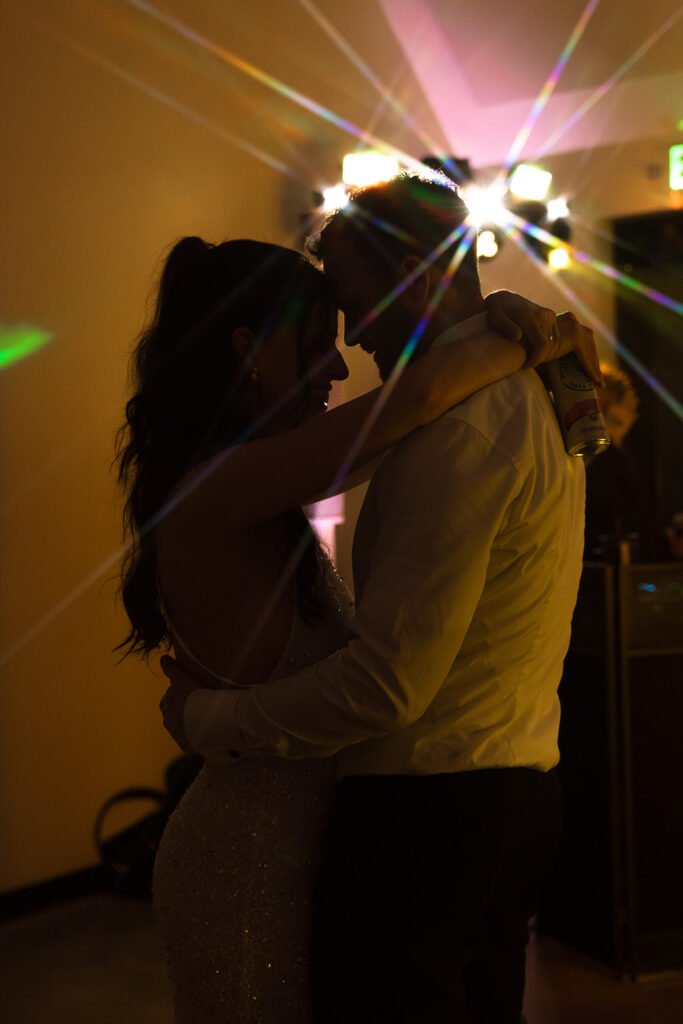 The couple slow dances in a corner of the reception, soft light spilling across them.
