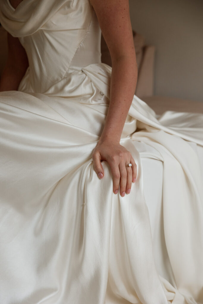 Silk gown pooled at her lap while she waits for the next moment in posed wedding photography that looks straight out of a painting.