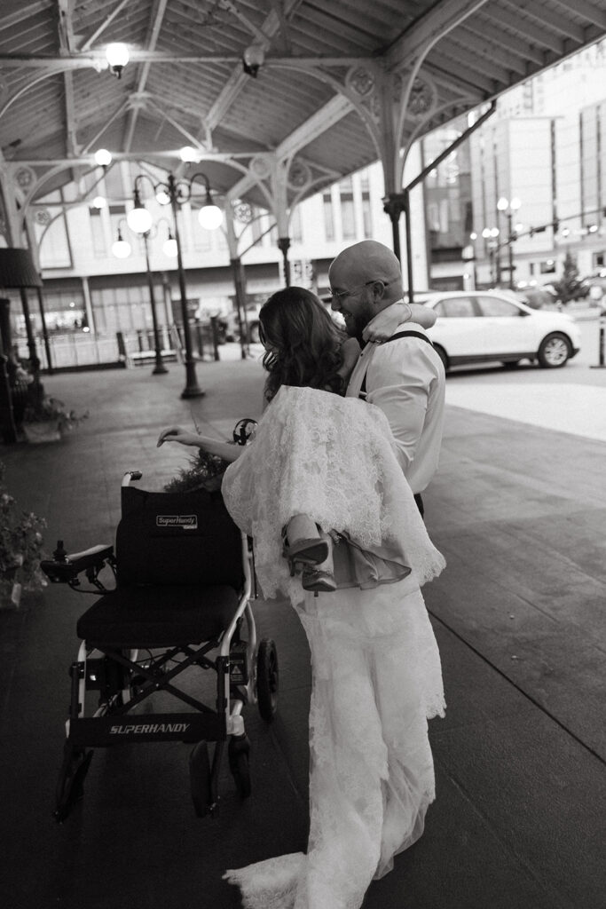 Groom lifts his wife into her wheelchair on their wedding day at Union Station in Nashville.