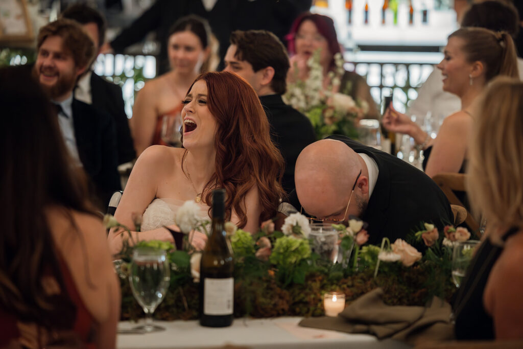 Bride and groom double over in raucous laughter during speeches at their Union Station wedding in Nashville, as captured by documentary wedding photographer Ali Miller