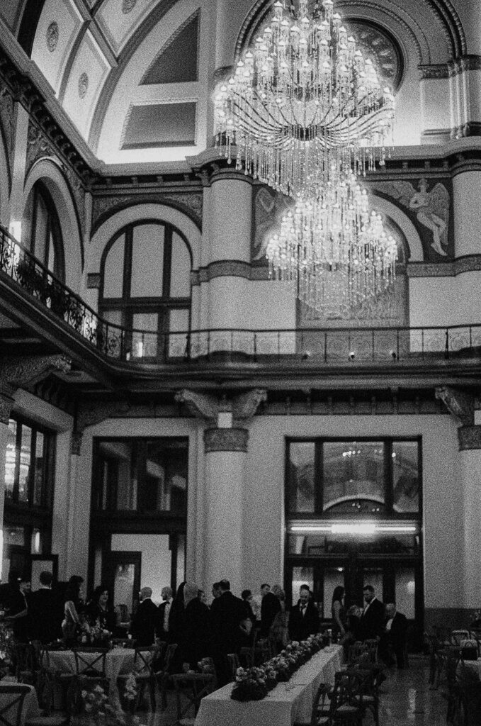 Wide shot of glimmering chandeliers at Union Station in Nashville while guests socialize during cocktail hour below.