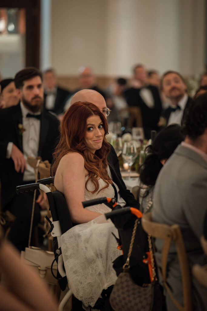 Bride exchanges a knowing look with a wedding guest as jokes are made during wedding speeches, as captured by documentary wedding photographer