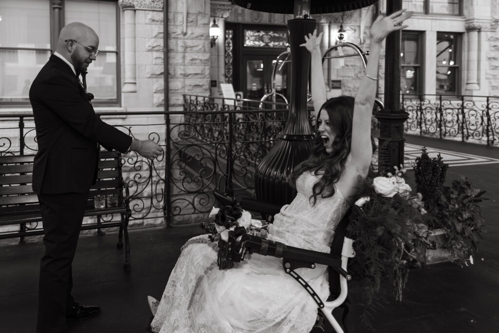 Comedian Fiona Cauley lifts her hands up in total jubilation while her husband fixes his cuff link at their wedding at Union Station in Nashville