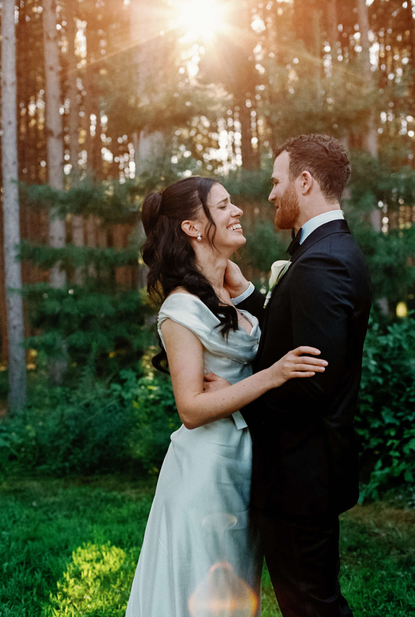 Groom and bride embracing one another during golden hour in the woods of Pinewood Weddings and Events in Cambridge Minnesota