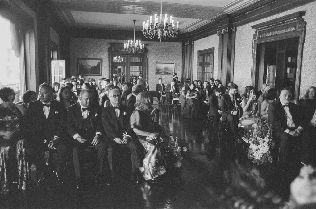 Room of wedding guests waits patiently for brides to come down the aisle at University Club of San Francisco wedding ceremony