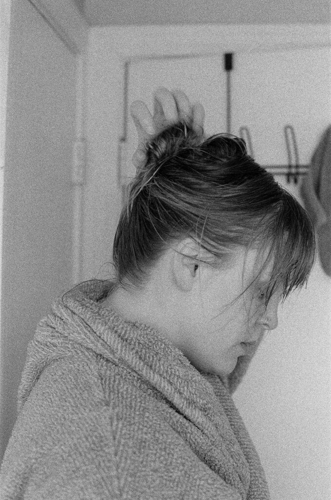 Side profile of Minnesota and Nashville photographer Ali Miller twisting her damp hair into a messy bun during an in-home branding session.