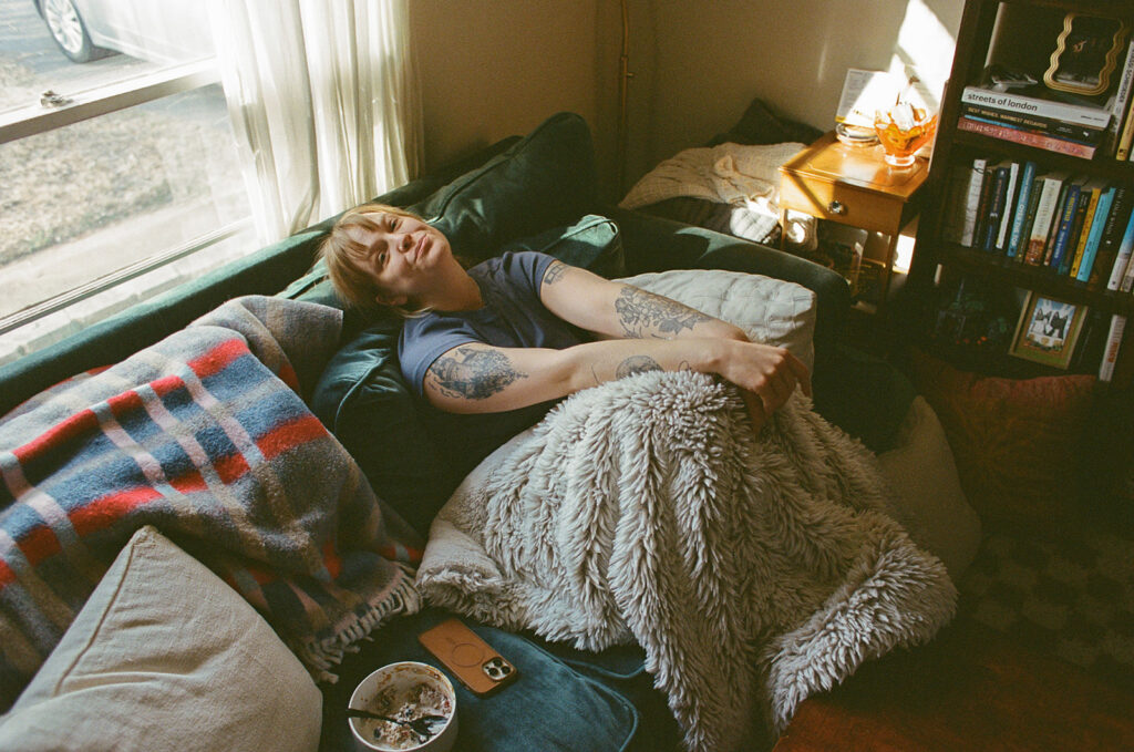 Documentary portrait of Nashville photographer Ali Miller resting beneath a cozy blanket during a slow morning at home.