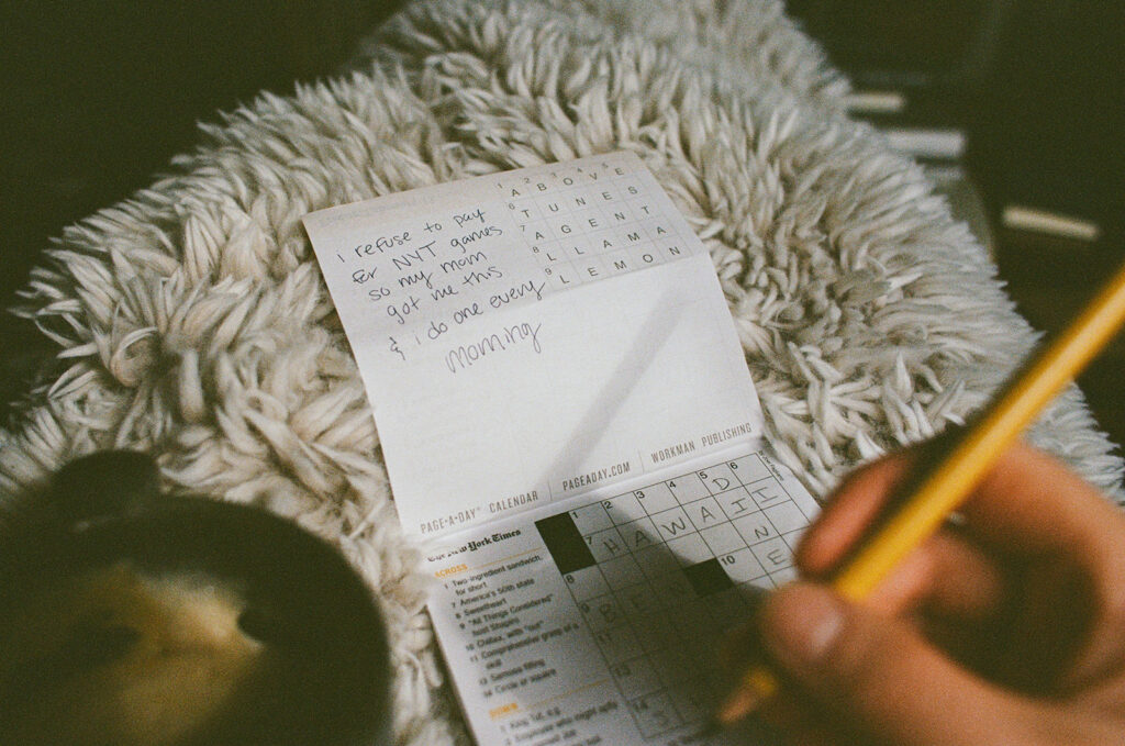 Close-up documentary photograph of a crossword puzzle and handwritten note reflecting Ali Miller's everyday morning ritual.