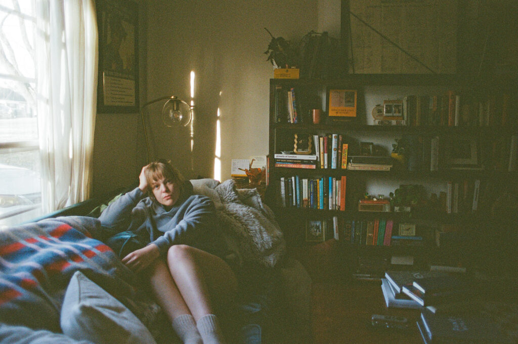 Documentary-style portrait of Nashville photographer Ali Miller relaxing on her couch surrounded by books and afternoon light.
