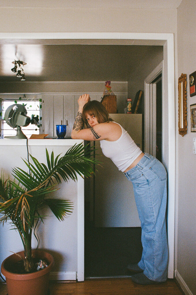 Nashville photographer Ali Miller leaning over a half wall inside her bungalow during playful documentary branding portraits.