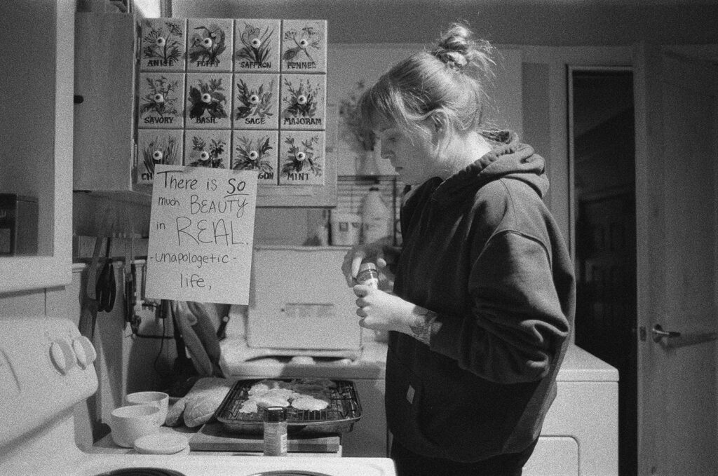 Documentary photograph of Nashville photographer Ali Miller preparing breakfast beneath a handwritten reminder celebrating real, ordinary life.