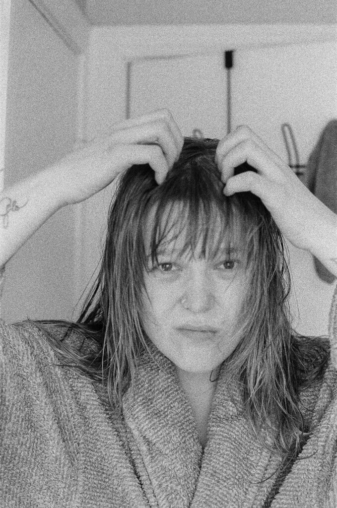 Candid self-portrait of Nashville photographer Ali Miller styling her wet hair in a robe as part of an authentic documentary photography session.
