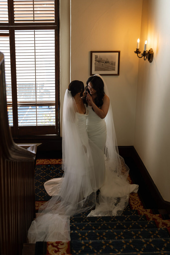 Lesbian brides share a private moment in staircase of University Club of San Francisco