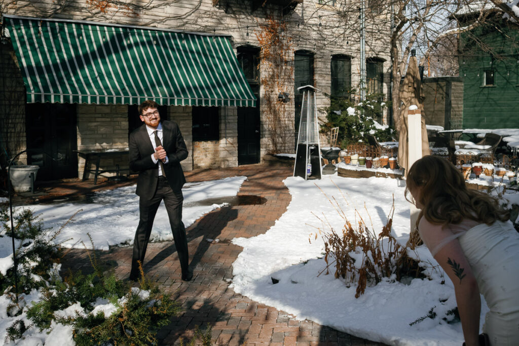 Bride and groom laugh out in the snow in Minnesota after groom accidentally messes up first look