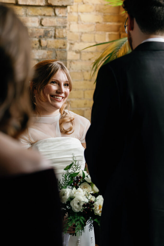 Bride smiles up at her groom during vows at Minnesota wedding