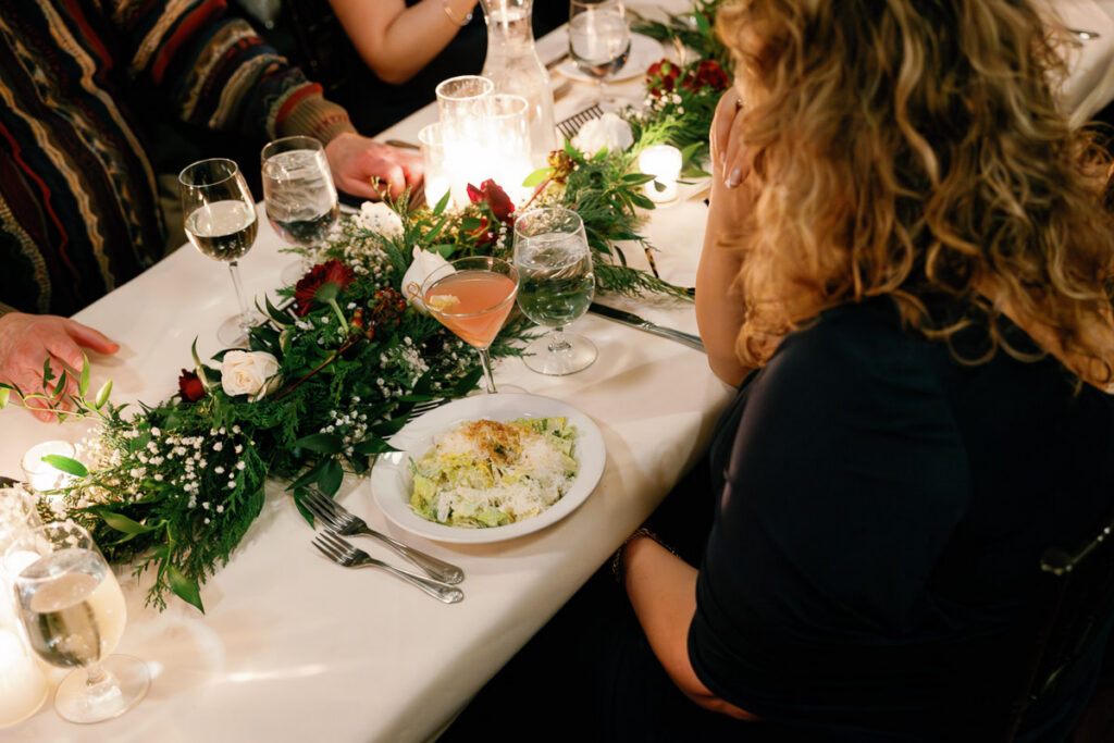 Wedding guest looks down at gorgeous plate of food on candlelit reception table at WA Frost and Company