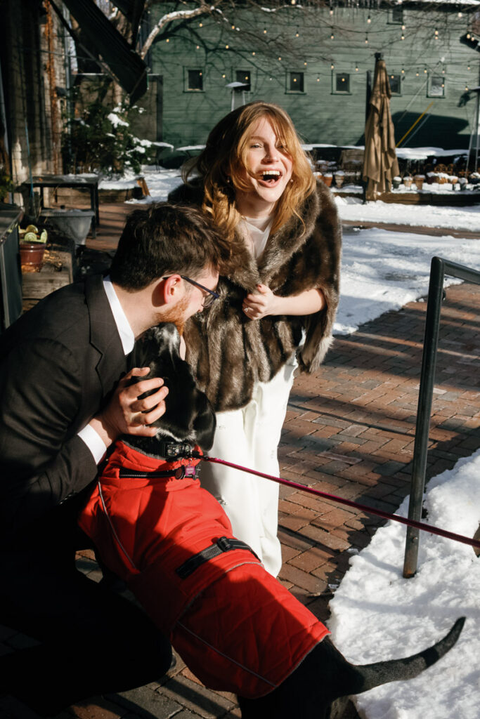 Bride in fur coat doubles over with joy and laughter when her dog makes a surprise appearance at her Minnesota wedding