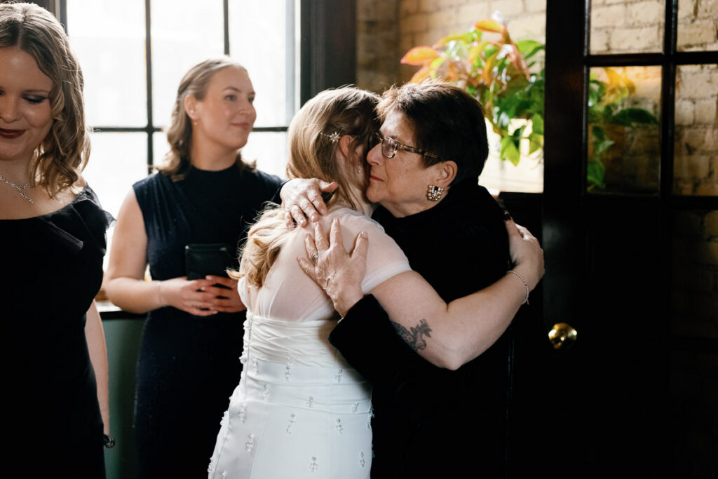 Grandmother of the bride holds bride close during emotional moment of authentic wedding photography